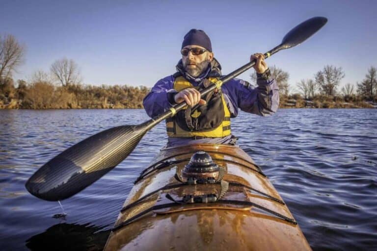 Man paddling kayak with deck mount compass on bow